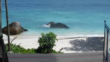Ein Strand mit klarem, blauem Wasser, großen Felsen und einem sandigen Ufer.