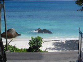 Una playa con aguas azules cristalinas, rocas grandes y una orilla arenosa.