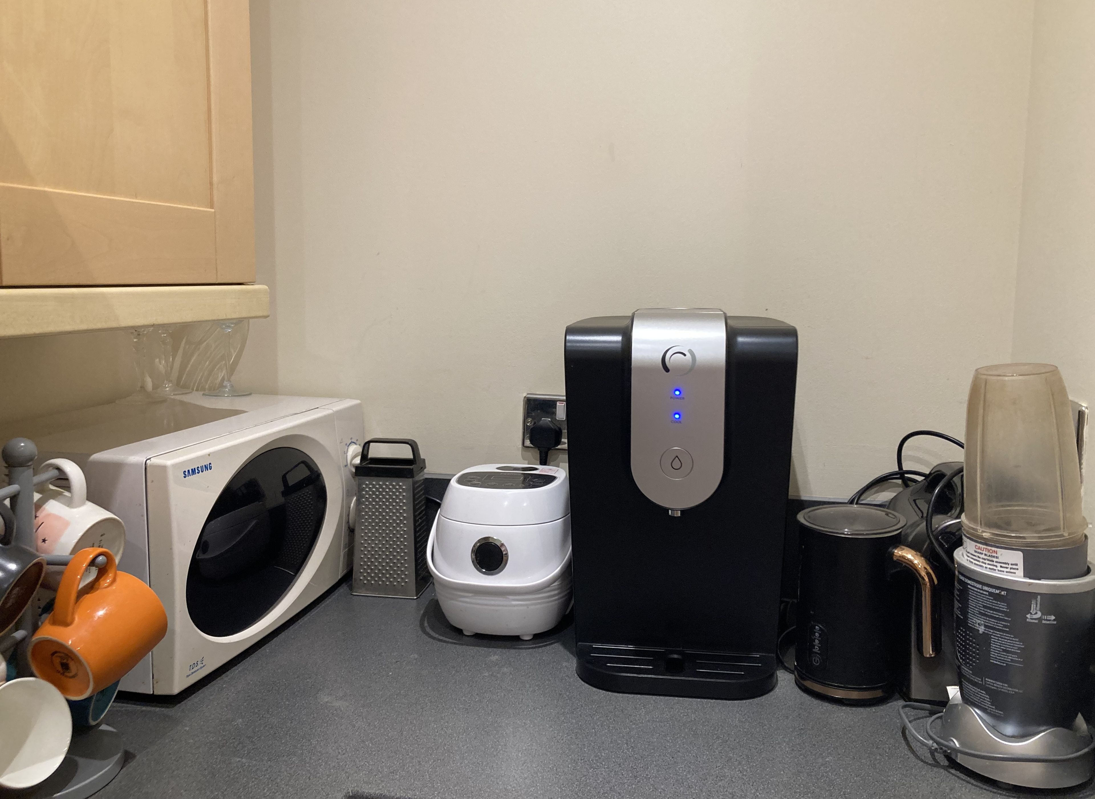 A kitchen with a microwave, coffee maker, and a blender on the counter.