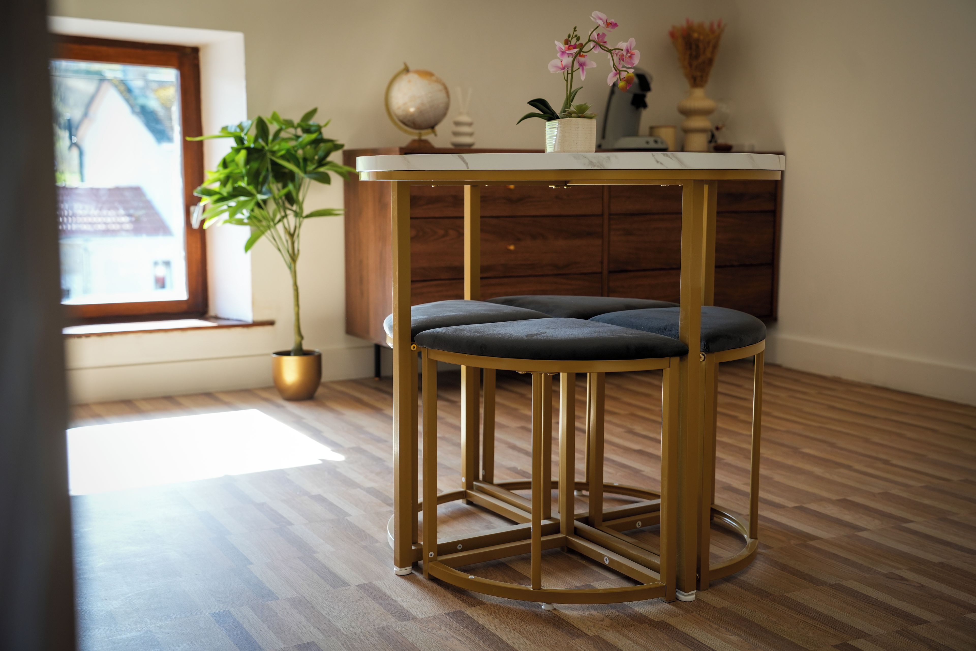 Un taburete redondo con marco dorado y asiento acolchado en una habitación con suelo de madera.