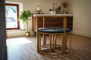 A round, gold-framed stool with a cushioned seat in a room with wooden flooring.