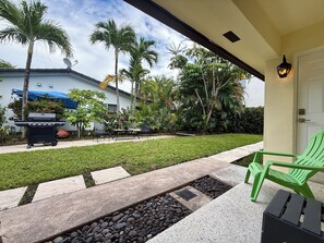 A patio with a grill, outdoor furniture, and a well-maintained lawn. - Pompano Vibes Beach Apartments (Pompano Beach)