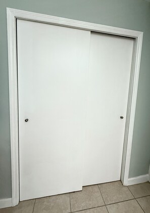 A closed white door with a simple handle, set in a room with light-colored walls and a tiled floor.