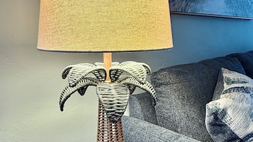 Une lampe avec un abat-jour texturé et un pied en osier, posée sur une table d’appoint en bois.
