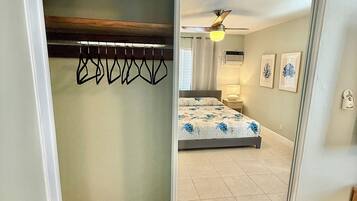A room with a bed, a ceiling fan, and a closet with a coat rack.