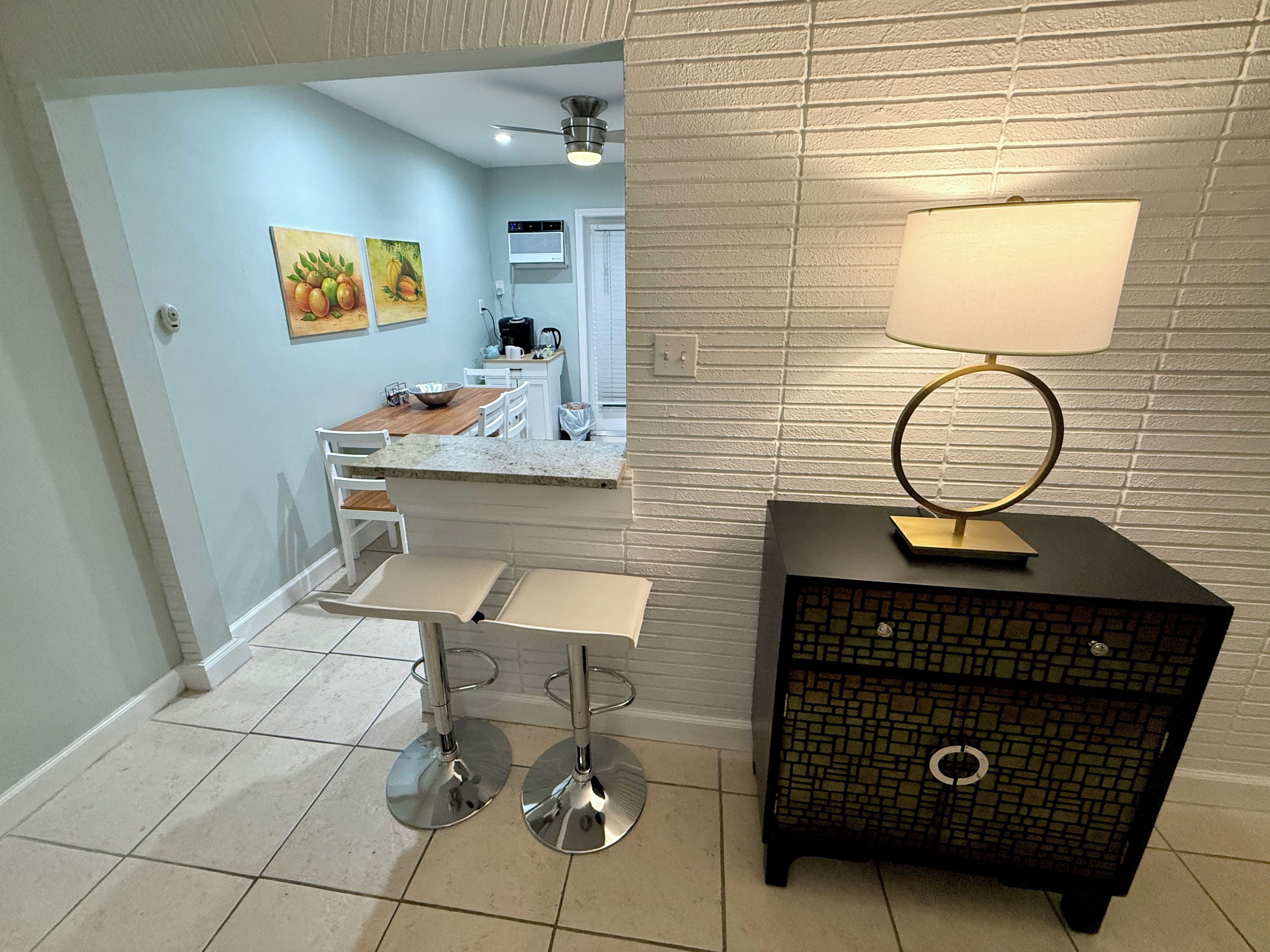 A modern kitchen with a dining area, a coffee machine, and a decorative lamp.