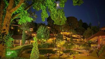Un espacio exterior bien iluminado con piscina, mobiliario y una escalera que conduce a un edificio.