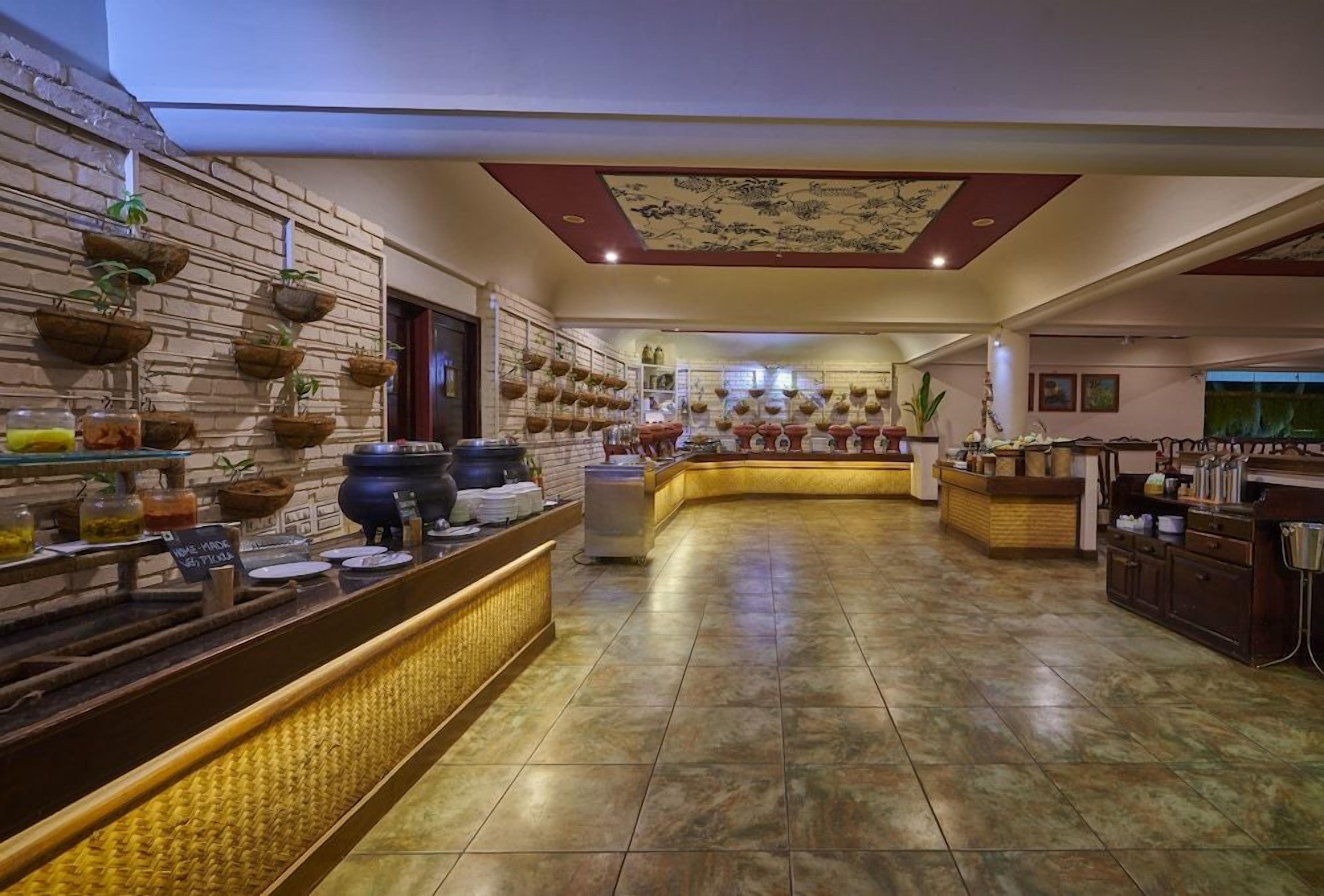 Un vestíbulo de hotel con una larga recepción, piso de baldosas y techo decorativo.