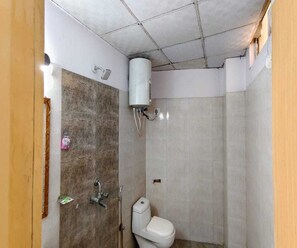 Ein kleines Badezimmer mit Dusche, Toilette und Warmwasserbereiter.