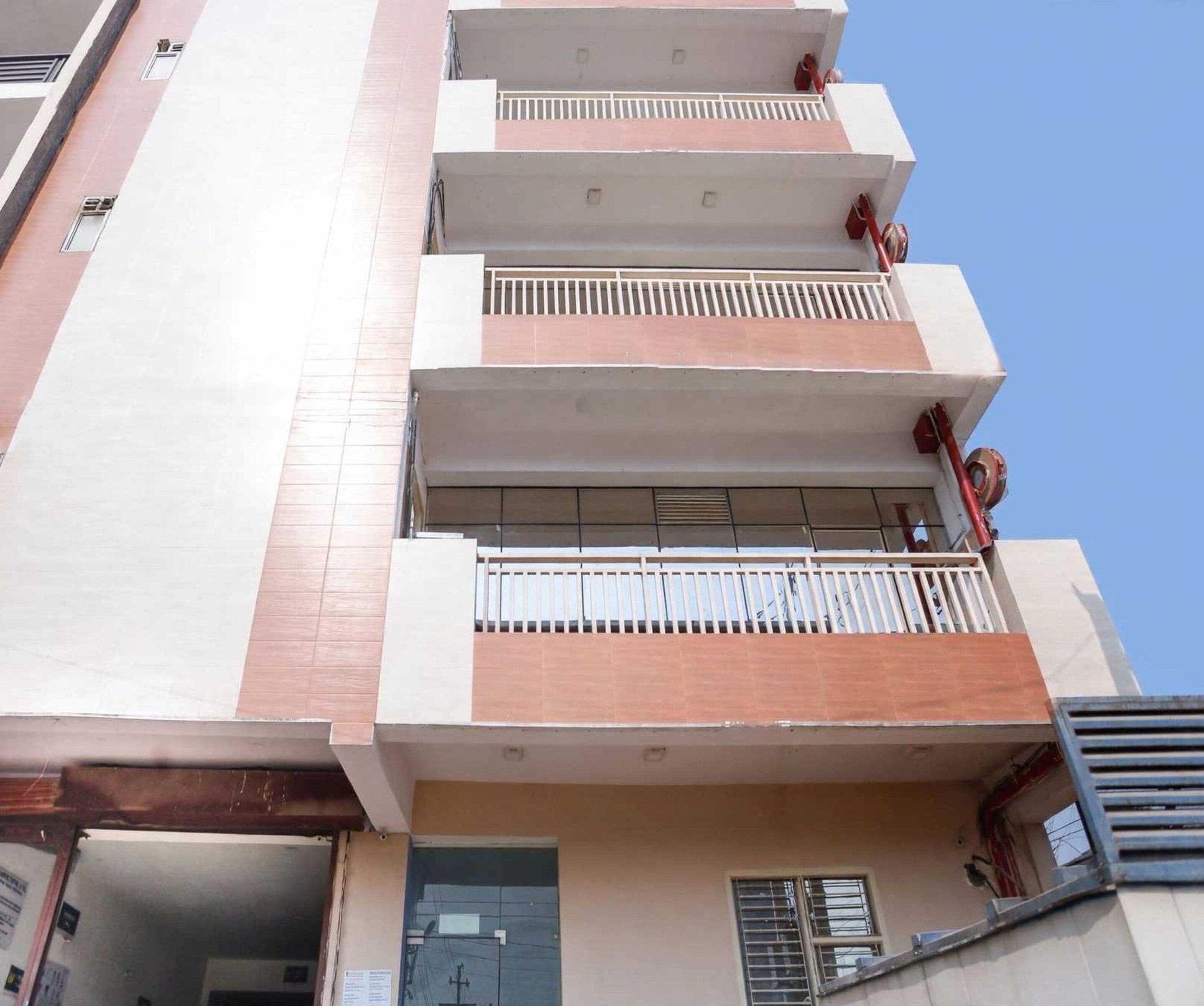 A multi-story residential building with balconies, a door, and a window.