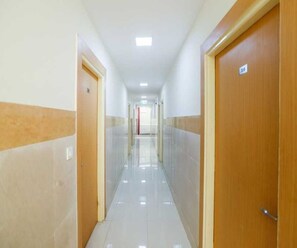 Ein Korridor mit Türen an beiden Seiten, einem gefliesten Boden und einer Decke mit eingelassener Beleuchtung.