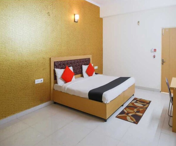 Una habitación de hotel con una cama, una mesita de noche, una lámpara y una puerta.