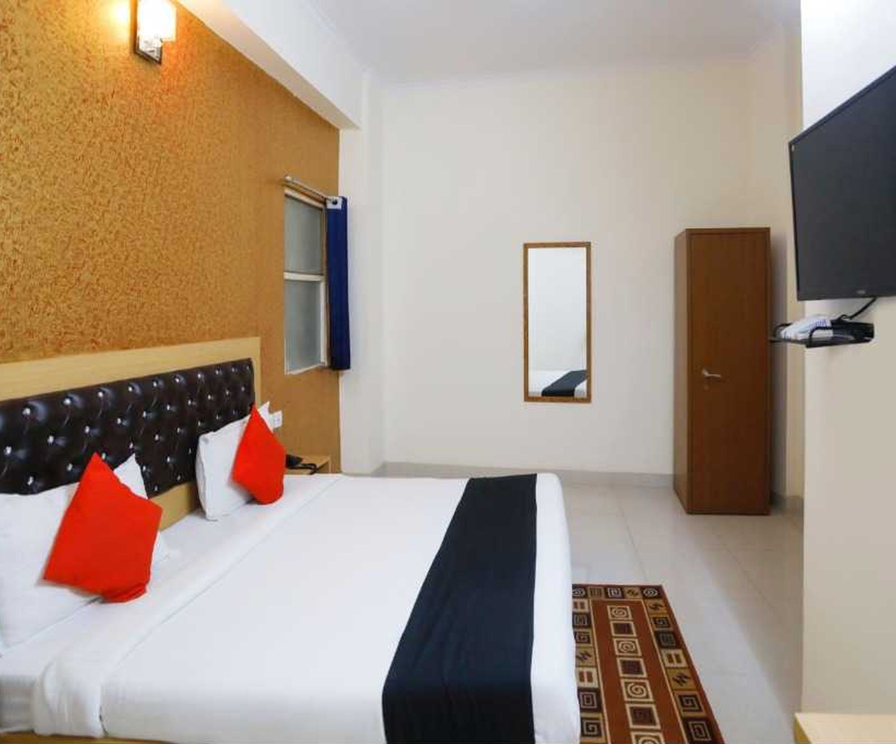 A hotel room with a bed, a wardrobe, a television, and a mirror.