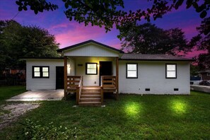 Einbungalow mit Veranda, einer sichtbaren Tür und einer kleinen angebauten Garage.