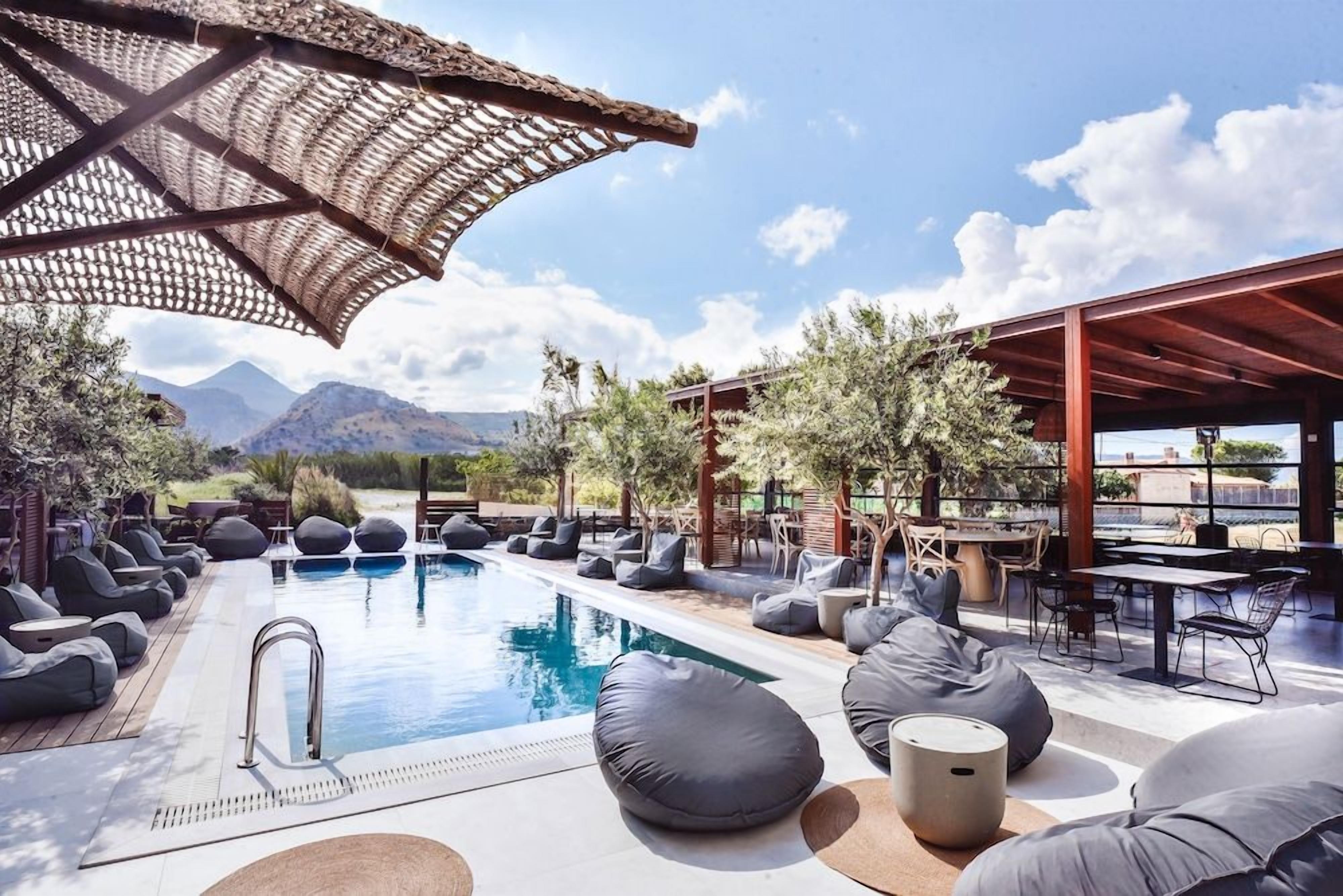 Zona junto a la piscina con sillones de descanso y una pérgola.