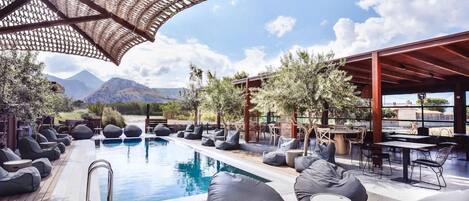Zona junto a la piscina con sillones de descanso y una pérgola.