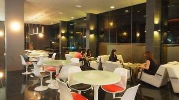 A modern restaurant interior with round tables and white chairs, featuring a polished floor and large windows.