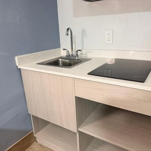 A kitchen with a double sink, a countertop, and a built-in stove. - Amerihill Inn Suites Greensboro (Greensboro)