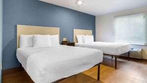 Habitació d'hotel amb dos llits, una finestra amb persianes i una làmpada al sostre.