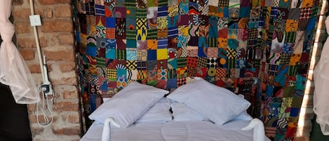 A bed with a colorful quilt, white pillows, and a blue blanket.
