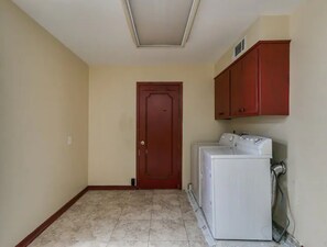 A laundry room with a washing machine, a dryer, and a door. - Spacious 7-bedroom home with heated pool and Jaccuzzi (Oklahoma City)