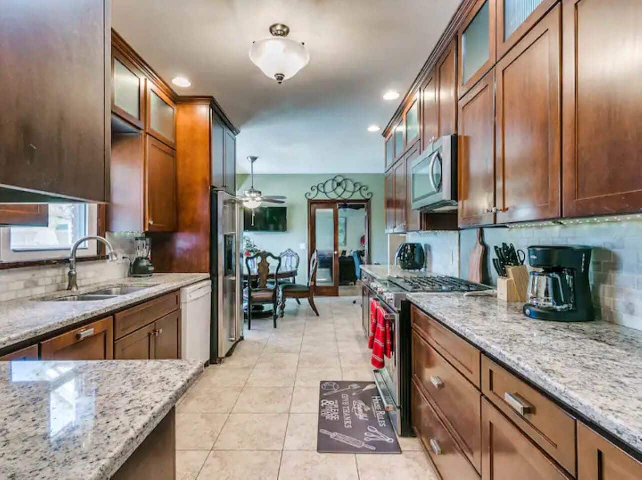 A kitchen with wooden cabinets, granite countertops, a refrigerator, stove, and a microwave.