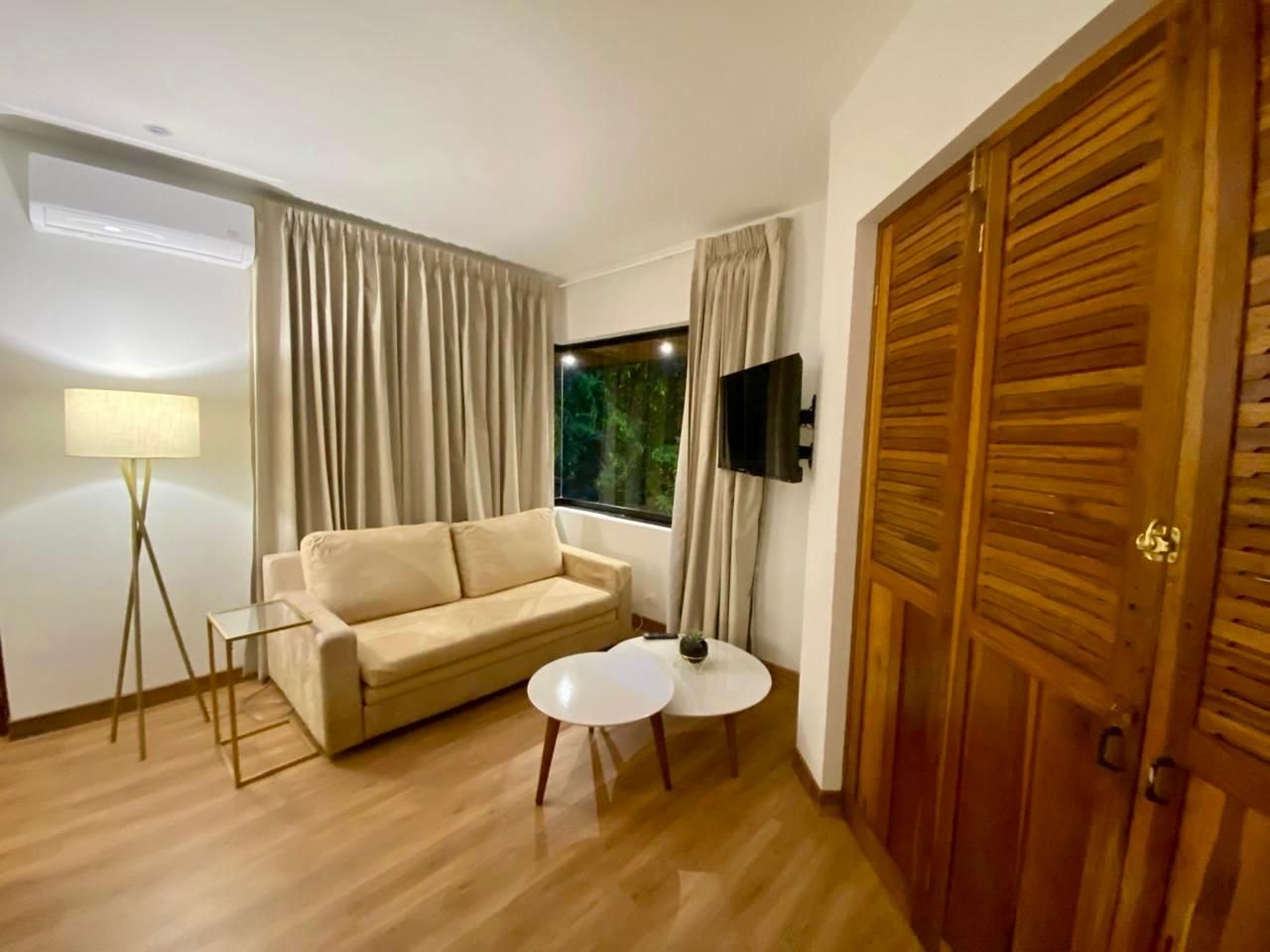 A room with a sofa, a small table, a lamp, a TV, and a wooden door.