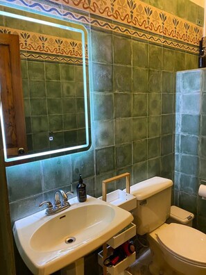 Ein Badezimmer mit einem weißen Waschbecken, einem Spiegel und einer Toilette.