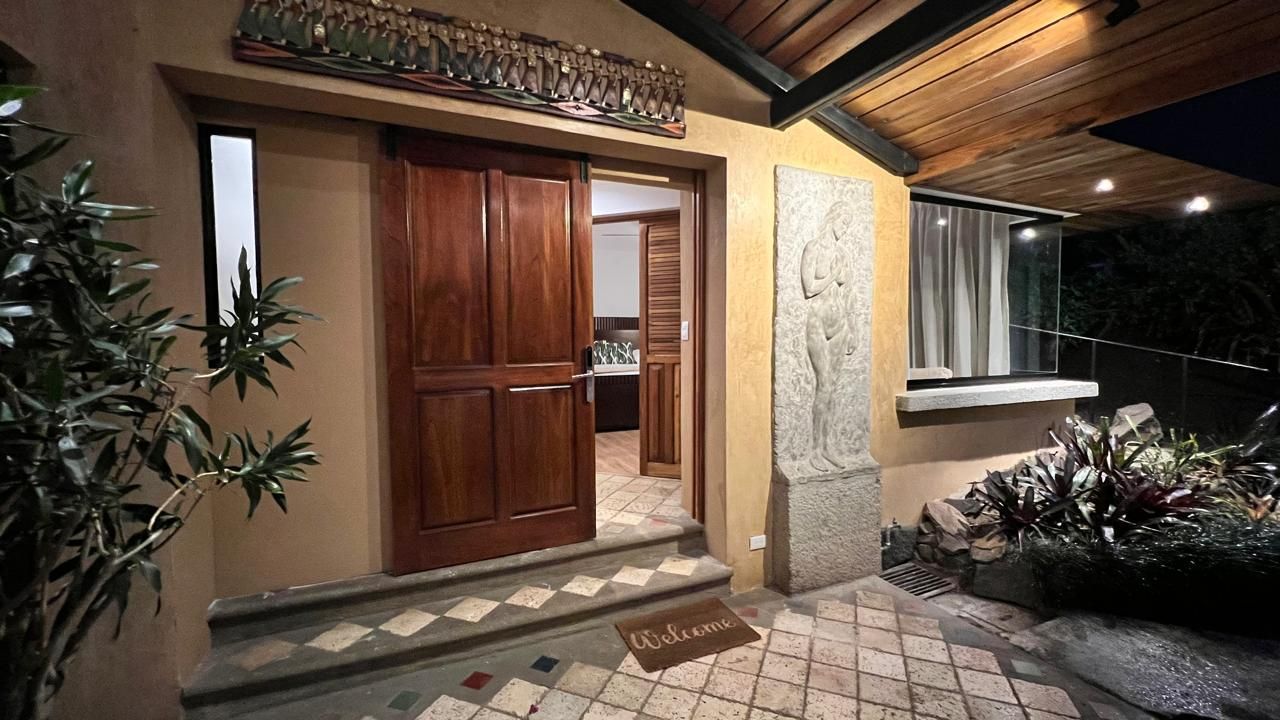 A house entrance with a wooden door, a welcome mat, and a stone wall.