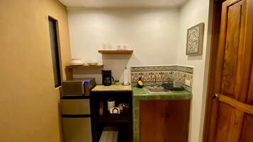 A compact kitchen with a refrigerator, a coffee maker, and a sink.