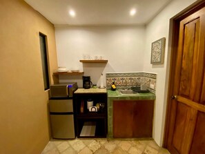 A compact kitchen with a refrigerator, a coffee maker, and a sink.