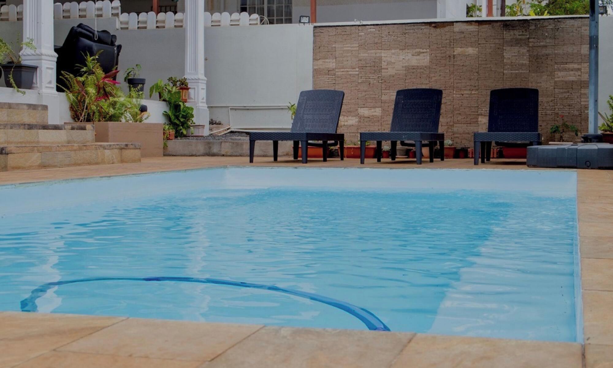 A swimming pool with lounge chairs and potted plants.