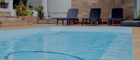 A swimming pool with lounge chairs and potted plants.