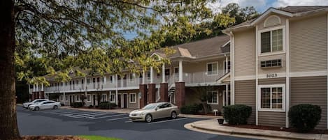 A multi-story hotel with a parking lot and a tree-lined street.