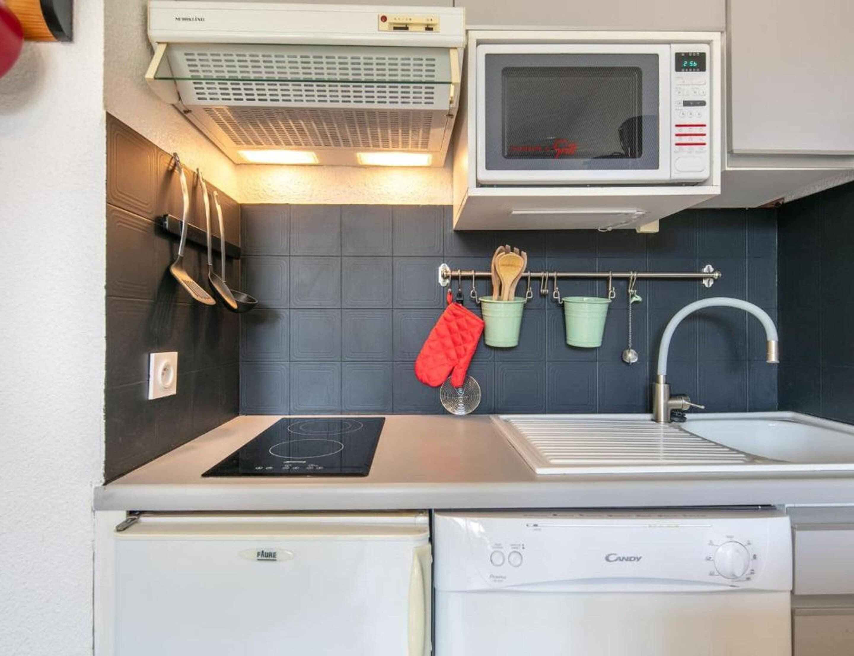 A compact kitchen with a microwave, stove, sink, and dishwasher.