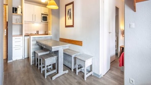 Una cocina compacta con una isla central, armarios de madera y una lámpara colgante.