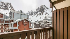 Un balcón con vista a montañas nevadas y edificios.