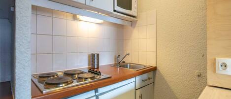 A compact kitchen with white cabinets, a microwave, a stove, and a dishwasher.