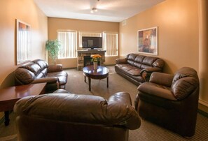 A living room with leather sofas, a coffee table, and a flat-screen TV. - Podollan Rez-idence Fort Mcmurray (Fort McMurray)