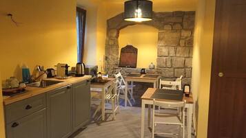 Uma cozinha compacta com um arco de pedra, porta de madeira e área de refeições com cadeiras brancas.