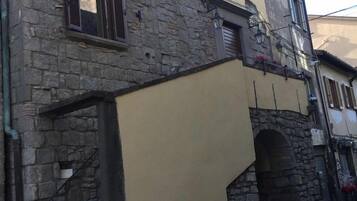 Um edifício com fachada de pedra, seção superior amarela e escadaria visível que leva a uma entrada.