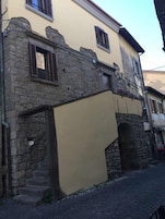 Un edificio con fachada de piedra, sección superior amarilla y una escalera visible que conduce a la entrada.