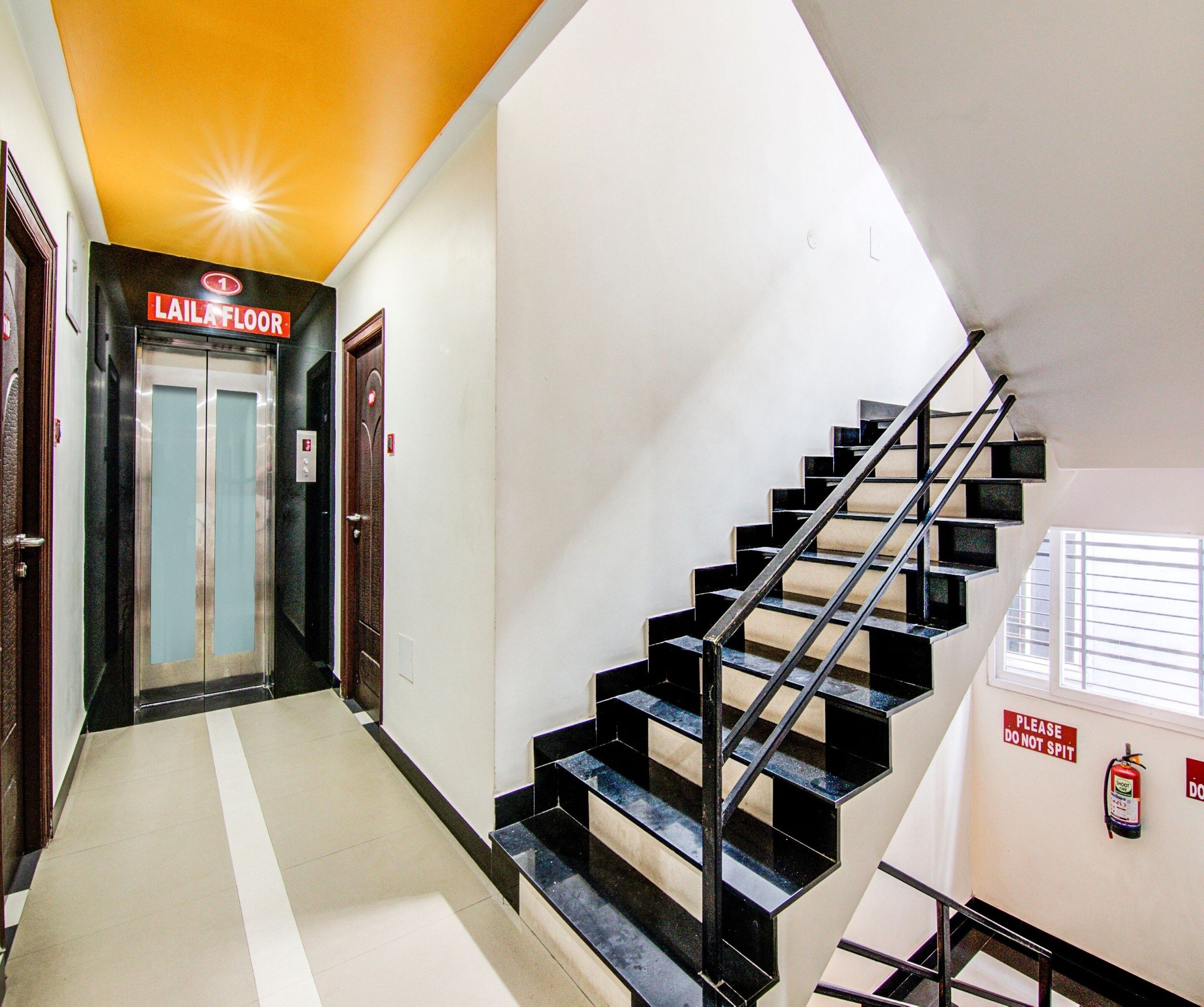 A hotel corridor with a staircase, a fire extinguisher, and a sign indicating the floor level.