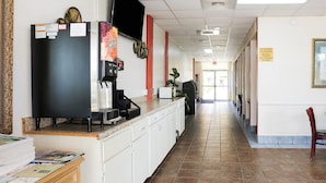 A hotel lobby with a reception desk, a coffee machine, and a plant. - Magnuson Hotel Opelika (Opelika)