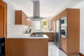 Une cuisine moderne dotée d’un îlot central, d’appareils électroménagers en acier inoxydable et de meubles de rangement en bois.