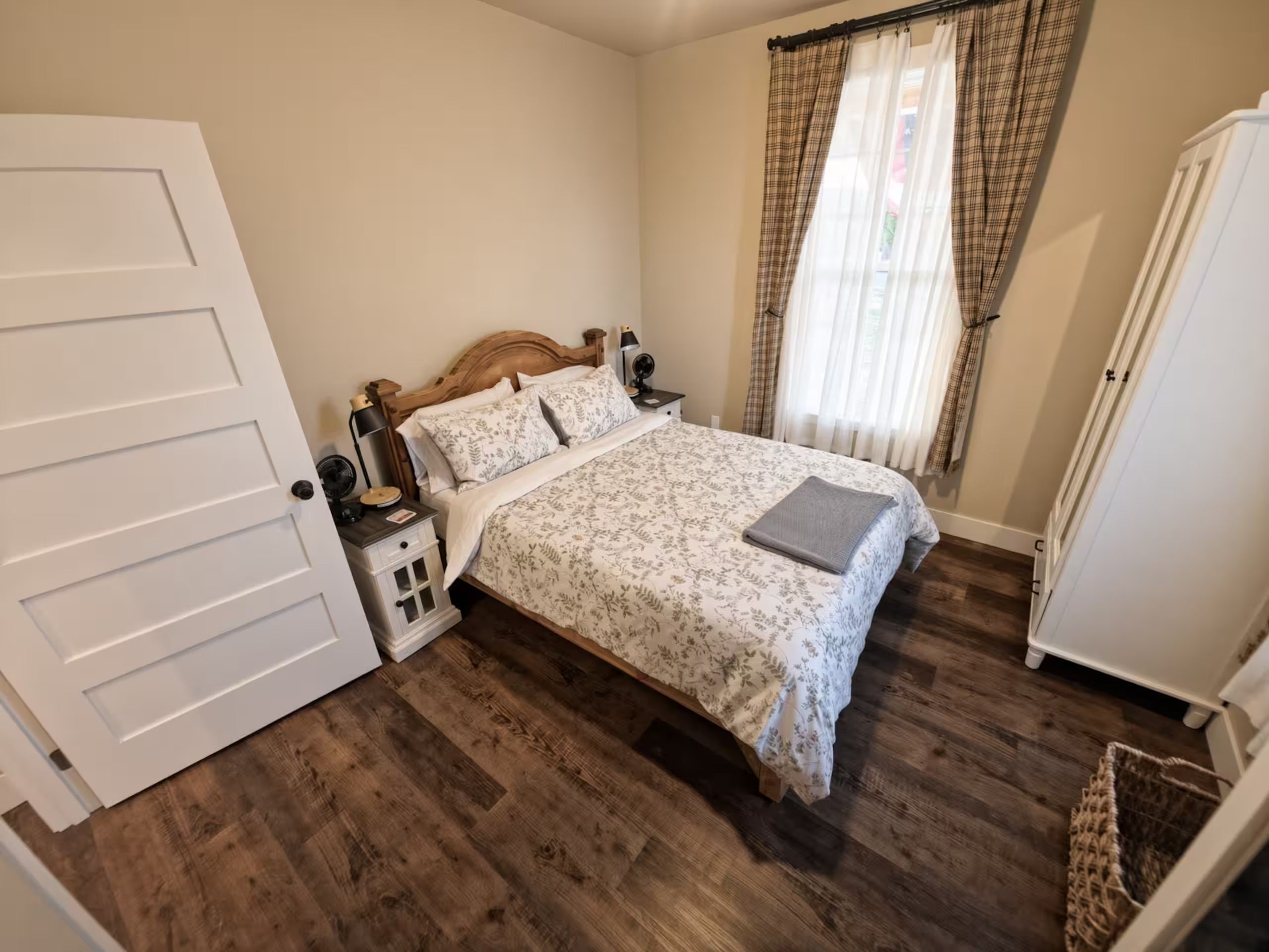 A bedroom with a wooden bed, a nightstand, a bedside table, a radiator, and a wardrobe.