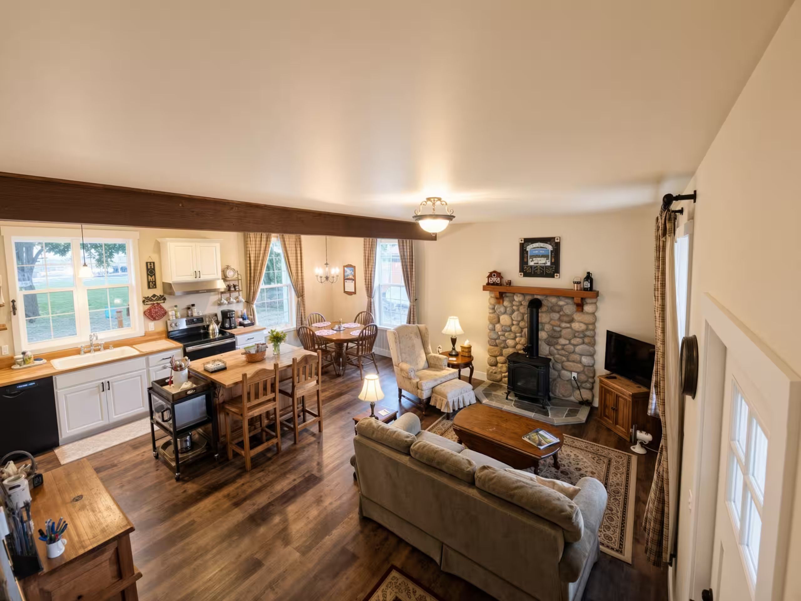 Een ruime woonkamer met een open haard, een eettafel en een keuken met moderne apparatuur.
