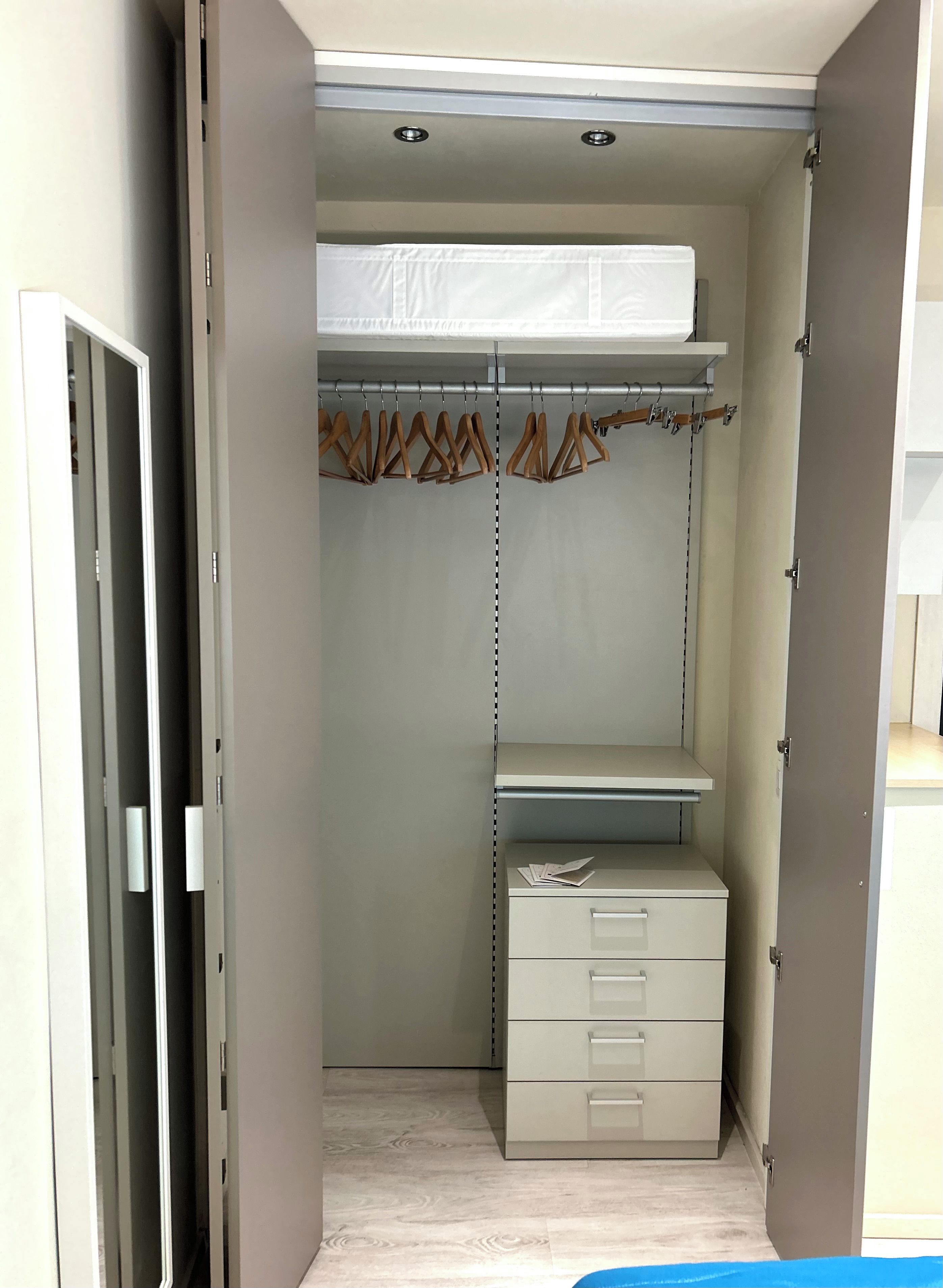 A walk-in closet with a hanging rod, a shelf, and a set of drawers.