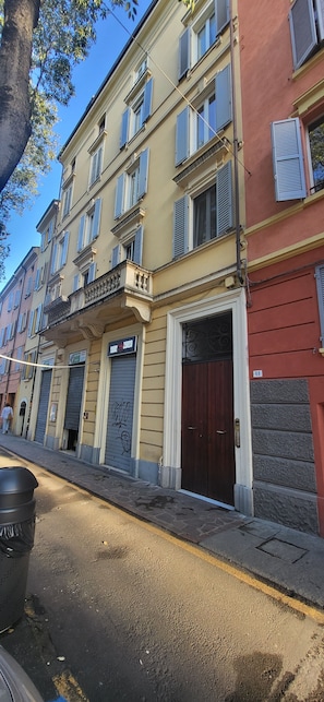 Un edificio a più piani con un negozio al piano terra, persiane chiuse e una porta marrone scuro.