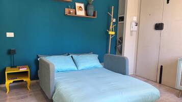 Une chambre à coucher avec un lit, une table de chevet avec une lampe et une étagère murale avec des livres et un vase.